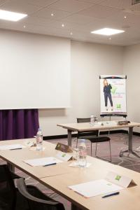 a conference room with tables and a presentation on a screen at Ibis Barcelona Santa Coloma in Santa Coloma