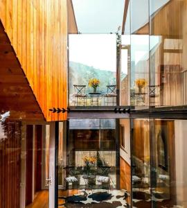 een huis met glazen wanden en een balkon met tafels en stoelen bij Hotel Casa Zapallar in Zapallar