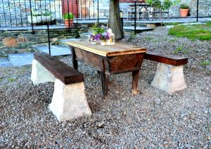 une table en bois et un banc avec des fleurs. dans l'établissement Apartamentos Rurales RON, à Ron