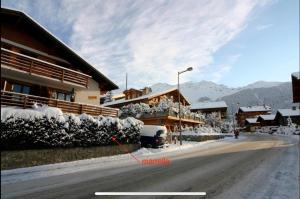 a snow covered street in front of a building at Marelle Apartment, Verbier in Verbier