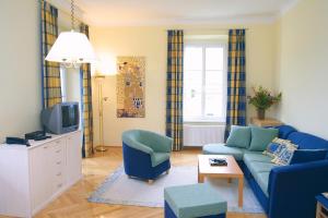 a living room with a blue couch and a tv at Villa Engstler - Appartments in Velden am Wörthersee