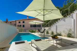 een zwembad met een parasol en twee stoelen en een tafel bij Casa Mia Apartments in Premantura