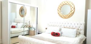 a bedroom with a white bed with a mirror at Gabriel Guesthouse in Rhyl