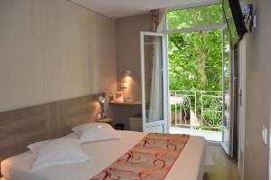 a bedroom with a bed and a large window at Hotel Le Revest in Sainte-Maxime