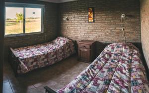 a room with two beds and a brick wall at El Retiro - Casa de campo en Los Reartes in Los Reartes