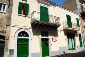 a building with green doors and a balcony at Le Cinque Luci in Modica