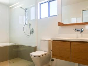 uma casa de banho com um chuveiro, um WC e um lavatório. em Fat Frog Beach Houses em Byron Bay