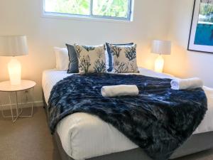 a bedroom with a bed with a blanket on it at Fat Frog Beach Houses in Byron Bay