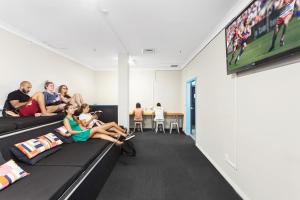 un grupo de personas sentadas en sofás en una habitación en Sydney Backpackers, en Sídney