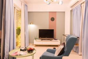 a living room with a tv and a blue chair at Guangzhou Haizhu·Pearl Shadow Star City· Locals Apartment 00138600 in Guangzhou