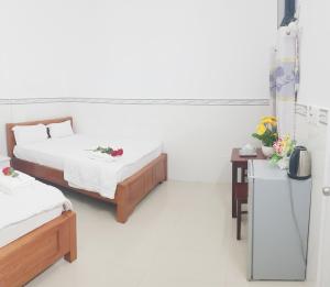 una habitación con 2 camas y una mesa con flores en Hai Phuong Tuyen Guesthouse, en Phu Quoc