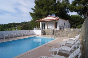 a swimming pool with white chairs and a house at Villa Elpiniki in Troulos