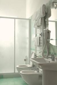 bagno bianco con 2 lavandini e servizi igienici di Hotel Ristorante Anita a Cupra Marittima