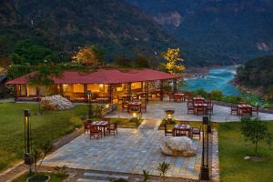 a restaurant with tables and chairs next to a river at Aloha On The Ganges by Leisure Hotels in Rishīkesh