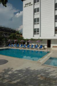 a swimming pool with blue lounge chairs and a building at Doruk Hotel & Suits in Marmaris