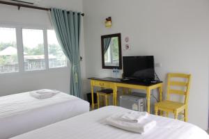 a bedroom with two beds and a desk with a television at Moeimanee Resort in Mae Sot