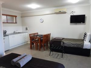 a bedroom with a bed and a table and a kitchen at Main Street Motel in Hervey Bay