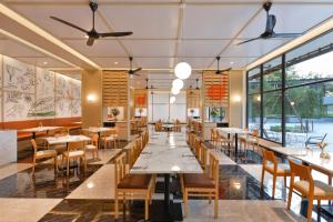 un restaurant avec des tables et des chaises et de grandes fenêtres dans l'établissement Tinidee Hotel Bangkok Golf Club - SHA Certified, à Pathum Thani