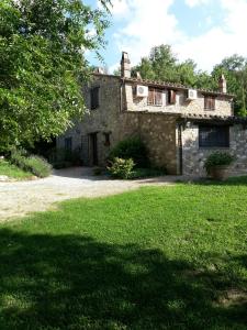 una antigua casa de piedra con un patio de césped en Casa Vacanze Le Corone, en Otricoli