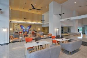 een lobby met tafels en stoelen en een vlindermuur bij Tinidee Hotel Bangkok Golf Club - SHA Certified in Pathum Thani
