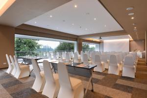 une salle de conférence avec des chaises et des tables blanches et une grande fenêtre dans l'établissement Tinidee Hotel Bangkok Golf Club - SHA Certified, à Pathum Thani