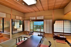 Zimmer mit einem Tisch, Stühlen und Fenstern in der Unterkunft Senjukaku in Yamanouchi