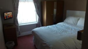 a bedroom with a white bed and a window at Royal Oakwell Hotel in Blackpool