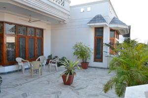 a patio with a table and chairs and plants at Sandy's Homestay in Jammu