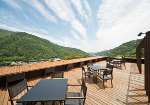 a deck with tables and chairs on a balcony at Aura Tachibana in Hakone