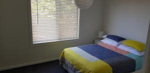 a bedroom with a bed with a colorful blanket and a window at 4 Bounty in Corinella