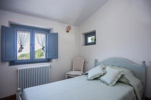 1 dormitorio con cama, ventana y silla en Podere La Contessa B&B, en Prato