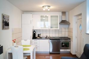a kitchen with white cabinets and a sink and a table at Apartment 1 Zimmer EG in Ratingen