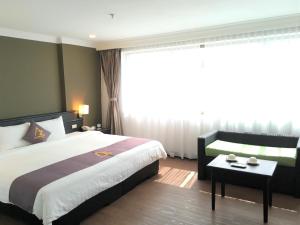 プノンペンにあるAzumaya Hotel Phnom Penhのベッドとテーブルが備わるホテルルームです。