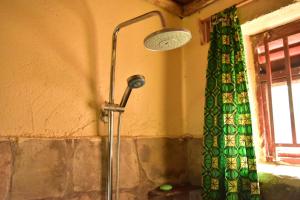 a shower in a bathroom with a green curtain at Red Rocks Rwanda - Campsite & Guesthouse in Nyakinama