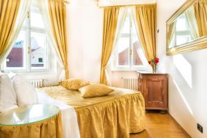 a bedroom with a bed with a table and windows at Charles Bridge Palace in Prague