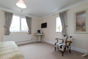 a bedroom with a bed and a chair and windows at Whitethorn Bed and Breakfast in Congleton