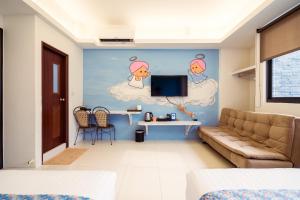 a living room with a couch and a tv on a wall at 安平72號民宿 in Tainan