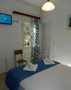 a bedroom with a bed with blue sheets and a window at Aggelos Studios in Agios Prokopios