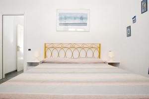 サンタ・テレーザ・ガッルーラにあるBilocale Via Cairoliの白いベッドルーム(大型ベッド1台、金のヘッドボード付)