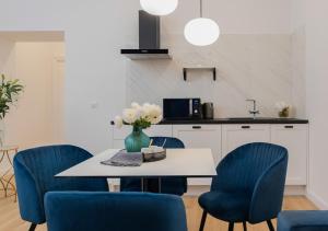 eine Küche mit blauen Stühlen und einem Tisch mit einer Blumenvase in der Unterkunft Pierrot & Pierrette in Zagreb