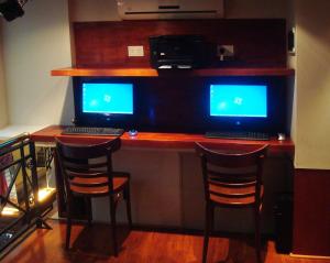 a computer desk with two monitors and two bar stools at Tanguero Hotel Boutique Antique in Buenos Aires