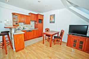 ソポトにあるGrand Apartments - Timber Apartment in Sopotのキッチン(木製キャビネット、テーブル、テレビ付)