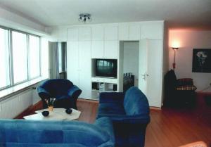 un soggiorno con 2 divani blu e una TV di Ferienwohnung-im-Wikingturm a Schleswig