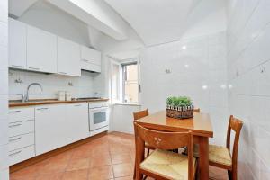 cocina con armarios blancos, mesa y sillas en Clementina Charme - My Extra Home, en Roma