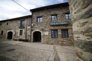 an old stone building with a sign on it at El Refugio Hostería in Rabanal del Camino