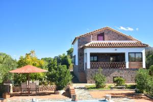 a house with a patio and an umbrella at Casa Rural Las Adelfas in El Gastor