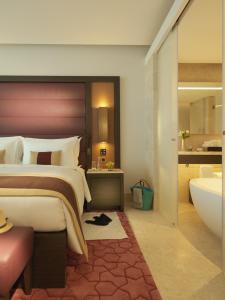 a bedroom with a large bed and a bath tub at Kempinski Hotel Muscat in Muscat