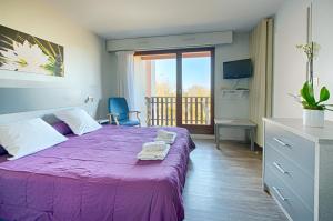 - une chambre avec un lit violet et un balcon dans l'établissement Résidence Espace Thermal, à Dax