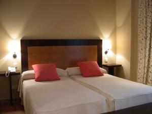 a hotel room with two beds and two lamps at Hotel Rural El Jardin de la Hilaria in Valsain
