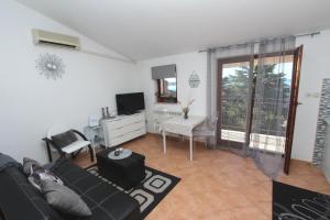 sala de estar con sofá negro y TV en Apartments Villa Nikola, en Rovinj